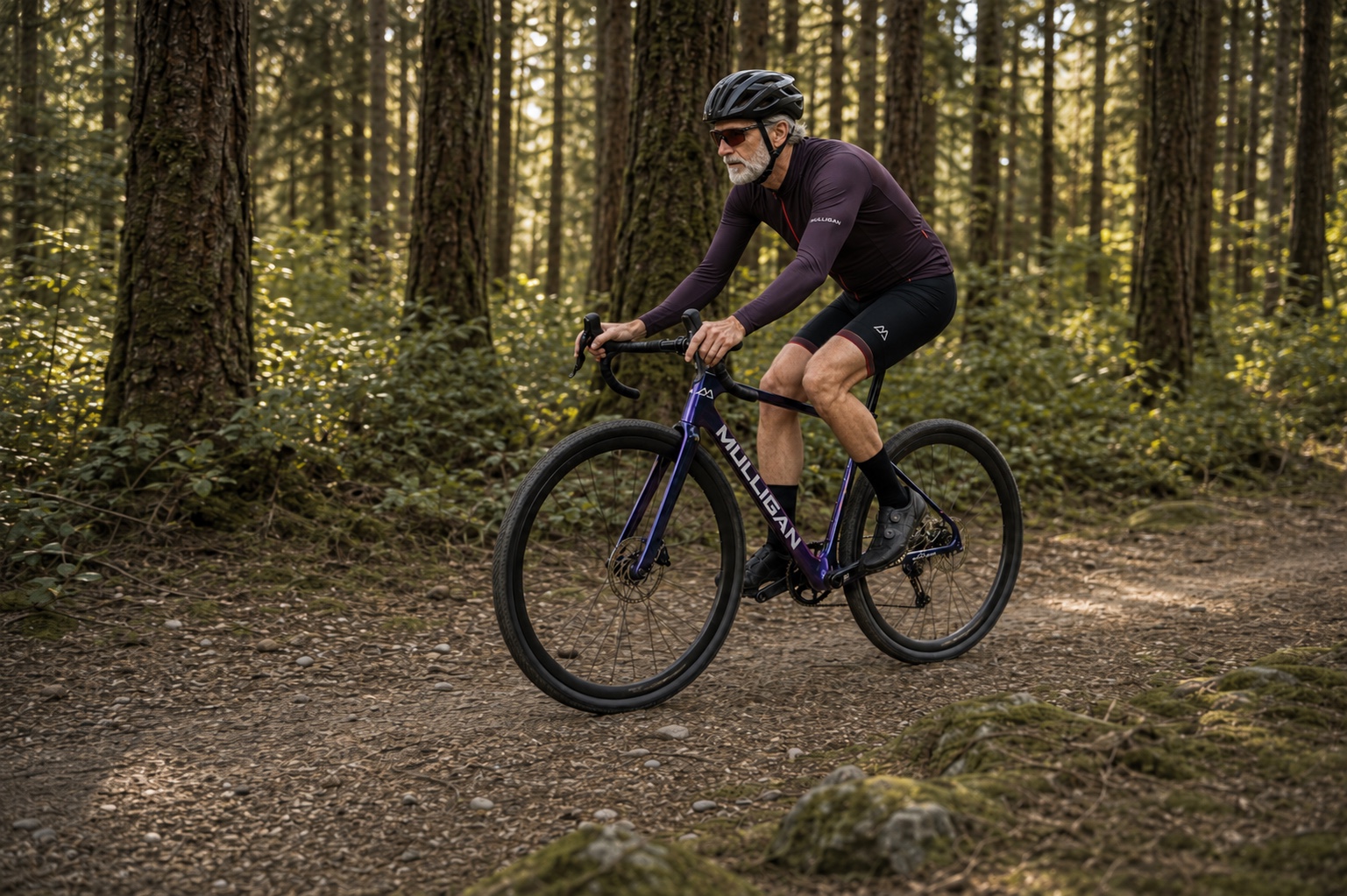 Vélo gravel carbone G1 MULLIGAN violet sur une piste forestière avec un cycliste roulant de droite à gauche.